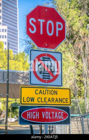 Schilder: Halten Sie an, fahren Sie nicht auf Schienen, Vorsicht bei geringer Abstände und Hochspannung - Downtown Tucson, AZ. Mehrere Straßenschilder auf einem Pfosten gegen die Ansicht eines Stockfoto