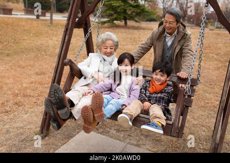 Glückliche chinesische Familie spielt auf einer Schaukel Stockfoto