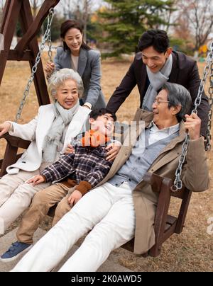 Glückliche chinesische Familie spielt auf einer Schaukel Stockfoto