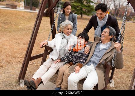 Glückliche chinesische Familie spielt auf einer Schaukel Stockfoto