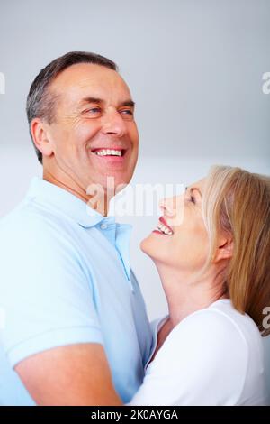 Das ältere Paar umarmt sich vor leerem Hintergrund. Nahaufnahme Porträt eines liebevollen älteren Paares umarmt sich gegenseitig vor leerem Hintergrund. Stockfoto