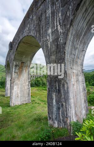Blick auf den hohen, schmalen und beeindruckenden Viadukt, der den ikonischen Jacobite Dampflokomotive-Zug trägt und sich durch die westlichen Highlands von Inve biegt Stockfoto