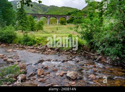 Weltberühmte Brücke, eingerahmt von grünen Bäumen, und engen Fluss, in den West Scottish Highlands, sehr beliebte Touristenattraktion und ikonisches Wahrzeichen, wegen es ist wie Stockfoto