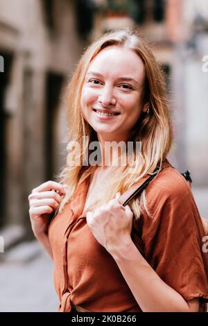 Junge blonde Frau, die während ihrer Ferien für ein Porträt posiert. Sie lächelt und schaut in die Kamera Stockfoto