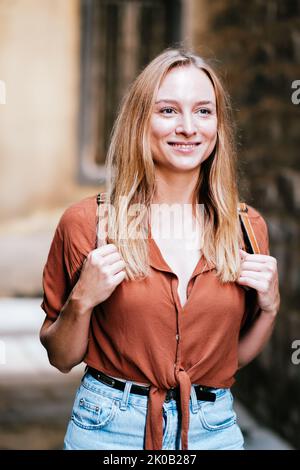 Fröhliche blonde weibliche Touristin, die mit ihrem Rucksack in die Altstadt von barcelona spazierengeht Stockfoto