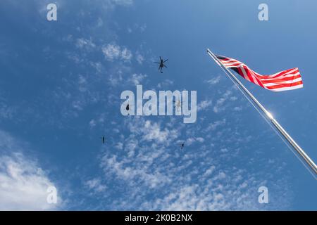 Silhouette von Hubschraubern, die in Formation über einem Fahnenmast mit Malaysias Flagge fliegen. Stockfoto