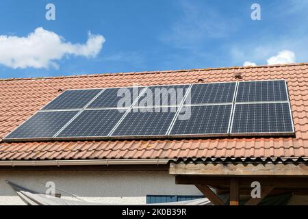Photovoltaik-Paneele auf dem Dach eines Hauses installiert. Sonnenkollektoren auf einem Dach. Stockfoto