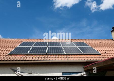 Photovoltaik-Paneele auf dem Dach eines Hauses installiert. Sonnenkollektoren auf einem Dach. Stockfoto