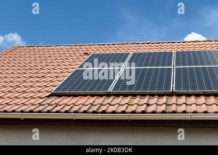 Photovoltaik-Paneele auf dem Dach eines Hauses installiert. Sonnenkollektoren auf einem Dach. Stockfoto