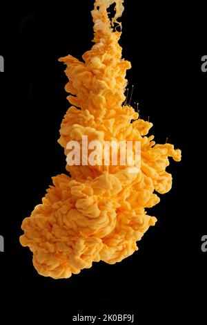 Und es war alles... gelb. Studioaufnahme von gelber Tinte im Wasser vor schwarzem Hintergrund. Stockfoto
