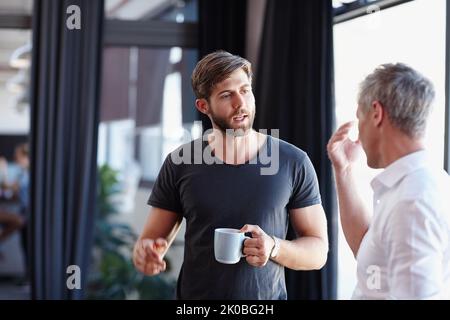 Tief in der Diskussion. Zwei gutaussehende Geschäftsleute, die eine Diskussion im Büro. Stockfoto