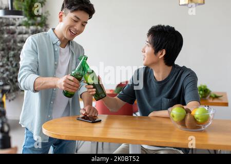 Glückliche junge chinesische Freunde trinken Bier Stockfoto