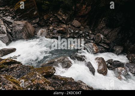 Ein steiniger Fluss fließt durch ein Tal in Neuseeland Stockfoto