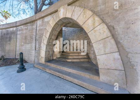 San Antonio, Texas - Bogenweg unter einer Brücke mit Ampeln an der Vorderseite. Beton gewölbt mit Treppe zwischen den Steinmauern. Stockfoto
