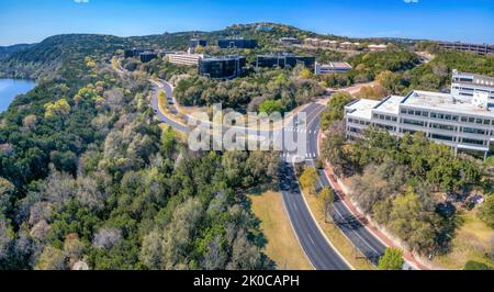 Austin, Texas - Luftaufnahme von Geschäftsgebäuden mitten im Wald in der Nähe des Flusses. Geschäftsviertel mit asphaltierten Straßen in der Nähe der grünen Berghänge Stockfoto