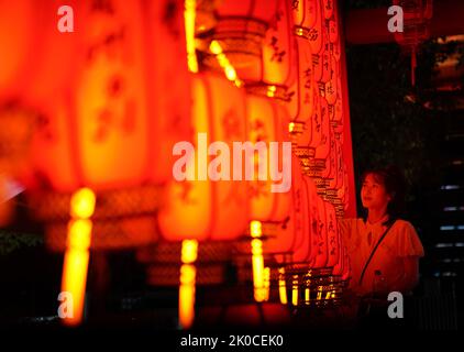 Nanchang, Chinas Provinz Jiangxi. 10. September 2022. Ein Besucher blickt auf Lichtinstallationen des Mid-Autumn Festival im Tengwang Pavillon in Nanchang, der Hauptstadt der ostchinesischen Provinz Jiangxi, am 10. September 2022. Quelle: Zhou Mi/Xinhua/Alamy Live News Stockfoto