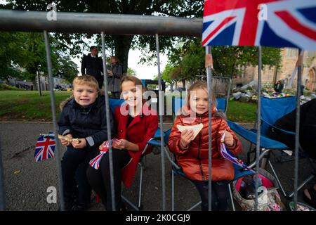 Ballater, Schottland, Großbritannien. 11.. September 2022. 3 Stunden vor dem Vorbeigehen der Cortege kommen junge Menschen in Ballater früh an. Hamish (8) Florence (11) und Gracie (5) kamen von Huntly und haben Sitze in der ersten Reihe. Ballater ist ein Dorf, das dem Balmoral Castle am nächsten liegt und sich heute auf der Route der Cortege befindet, die den Sarg von Königin Elizabeth II. Nach Edinburgh trägt. Iain Masterton/Alamy Live News Stockfoto