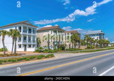 Dreistöckige Strandhäuser mit Balkonen und Palmen in der Nähe eines Strandes in Destin, Florida. Häuser mit Gehweg in der Nähe der Autobahn an der Vorderseite und eine Aussicht Stockfoto