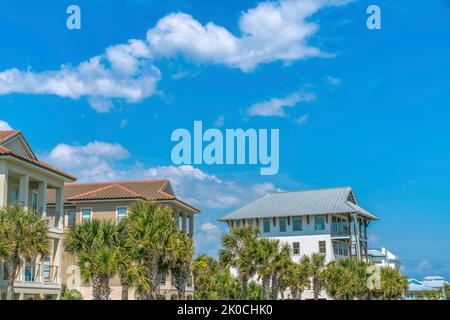 Destin, Florida - Palmen an der Vorderseite der Strandhäuser. Fassade von Häusern mit Balkonen vor dem Hintergrund des blauen Himmels. Stockfoto