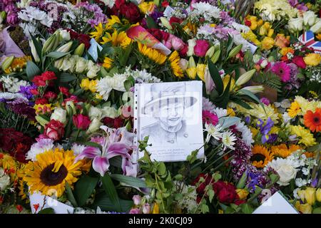 Eine Skizze von Königin Elizabeth II., die unter den Blumen zurückgelassen wurde, die von Mitgliedern der Öffentlichkeit in Balmoral in Schottland gelegt wurden. Der Sarg der Königin wird auf einer sechsstündigen Reise von Balmoral zum Palace of Holyroodhouse in Edinburgh transportiert, wo er ruhen wird. Bilddatum: Sonntag, 11. September 2022. Stockfoto