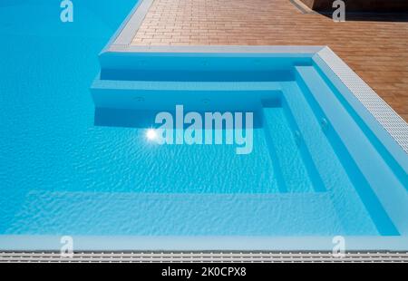 Swimmingpool mit Stufen in der Jacuzzi-Ecke mit Sonnenreflexion Stockfoto
