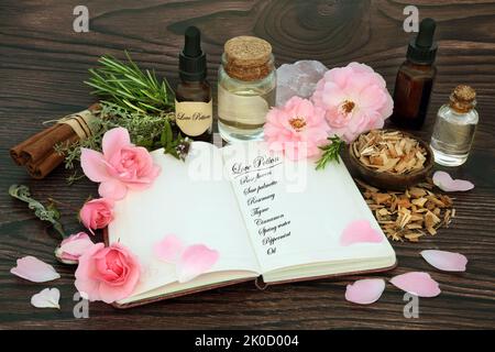 Love Trank Rezept Zutaten mit Magic Spell Notizbuch mit Kräutern, Rosenblüten, Öl, Quellwasser und Rosenquarzkristall. Mystischer Zauberer, Schamane Stockfoto