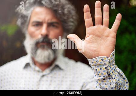 Bärtiger Mann in lässiger Kleidung, der mit der Hand eine Stoppgeste macht Stockfoto