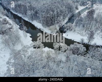 Verschneite Wälder und kurviger Fluss auf der Ebene im Winter. Luftaufnahme der Natur im Winter Stockfoto