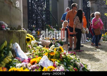 Die Mitglieder der Öffentlichkeit sehen Botschaften und Blumen, die vor dem Palace of Holyroodhouse in Edinburgh gelegt wurden. Der Sarg von Königin Elizabeth II. Reist von Balmoral nach Edinburgh, wo er im Palace of Holyroodhouse ruhen wird. Bilddatum: Sonntag, 11. September 2022. Stockfoto