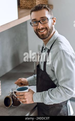 Bis zu schließen. lächelnden Mann Kaffee macht in seiner Küche Stockfoto