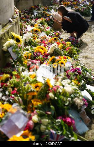 Die Mitglieder der Öffentlichkeit sehen Botschaften und Blumen, die vor dem Palace of Holyroodhouse in Edinburgh gelegt wurden. Der Sarg von Königin Elizabeth II. Reist von Balmoral nach Edinburgh, wo er im Palace of Holyroodhouse ruhen wird. Bilddatum: Sonntag, 11. September 2022. Stockfoto