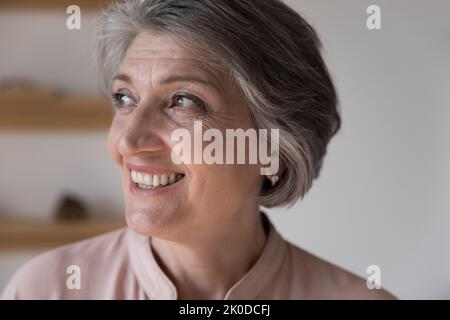 Glückliche verträumte Rentnerin grauhaarige Frau schaut weg Stockfoto