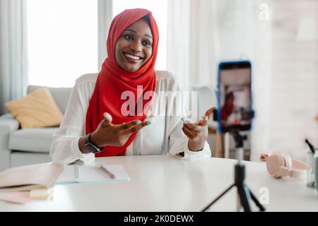 Glückliche afroamerikanische islamische Frau in Hijab Aufnahme neuer Video-vlog auf dem Smartphone oder macht Live-Stream Stockfoto