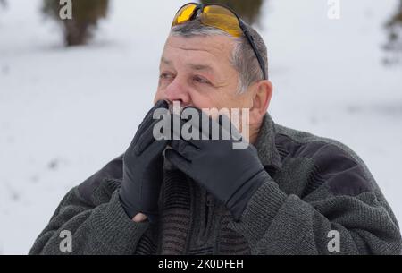 Porträt eines ukrainischen älteren Mannes, der mit Überraschung im Winterpark schaut Stockfoto