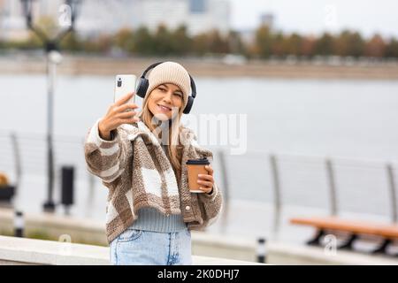 Junge Frau, die im Herbst ein Selfie mit ihrem Smartphone beim Spaziergang im Freien machte. Stockfoto