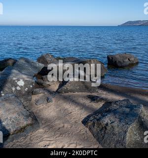 Felsbrocken als Teil eines Wellenbrechers in einem See. Bild vom See Vattern, Schweden. Blaues Wasser und Himmel im Hintergrund Stockfoto