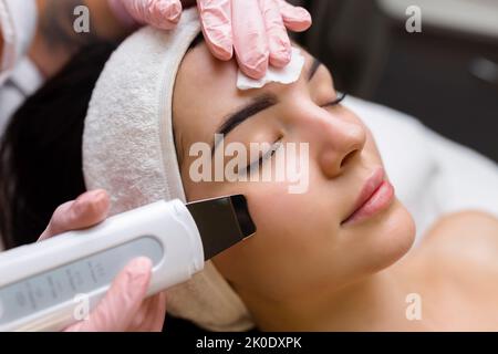 Gesichtsreinigung mit Ultraschall-Scrubber. Frau erhält Ultraschall-Gesichtspeeling und -Reinigung. Kosmetik- und Gesichtspflege. Gesichtsbehandlung Stockfoto