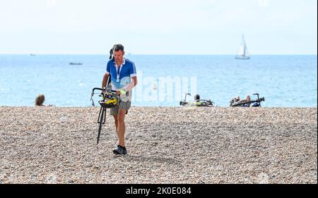 Brighton UK 11. September 2022 - Ein Radfahrer geht nach dem Fahrradausflug von London nach Brighton auf einen Spaziergang am Brighton Beach. Die Fahrt wird vielen Wohltätigkeitsorganisationen wie dem Great Ormond Street Hospital childrenÕs Charity : Credit Simon Dack / Alamy Live News Stockfoto