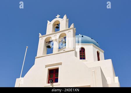 Oia, Santorini, Griechenland - 2022. Juni: Traditionelle griechisch-orthodoxe Kirche mit Glockenturm und blauer Kuppel in Oia Stockfoto