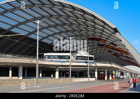 Amsterdam, Niederlande - August 2022: Öffentlicher Bus fährt unter seinem geschwungenen Dach am Amsterdam Centraal in den Busbahnhof ein. Stockfoto