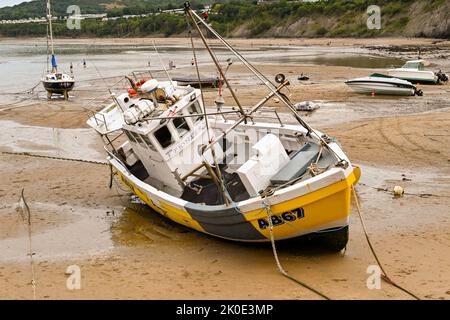 Newquay, Ceredigion, Wales - August 2022: Kleines Fischerboot, das bei Ebbe im Hafen auf Sand ruht Stockfoto