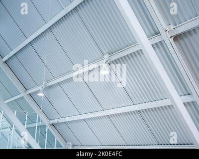 Scheinwerfer, der an der Dachkonstruktion des Hangaufbaus hängt. Moderne Deckenleuchten unter dem stilvollen Baugebäude im Dachgeschoss des weißen Hauses. Stockfoto