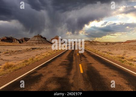 Die abgelegene Straße tief im Herzen des Petrified Forest National Park zeigt die wunderschöne Berglandschaft, die von einem stürmischen Himmel mit Regen umrahmt wird Stockfoto