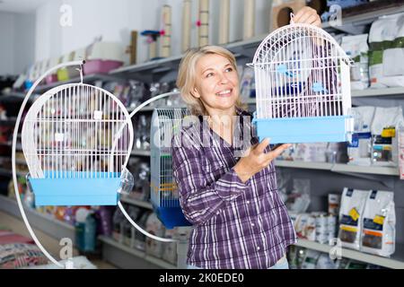 Frau kauft Käfig für Vogel im Geschäft Stockfoto