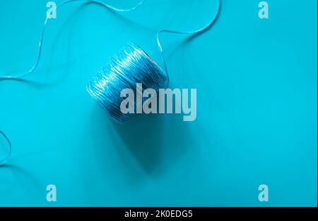 Eine Kugel aus blauen Fäden auf blauem Hintergrund, flach liegend. Stockfoto