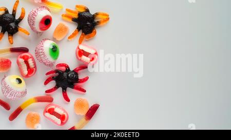 Close-up helle Gelee Süßigkeiten, Spinnen, Augen, Kiefer, Würmer und Fledermäuse, auf weißem Hintergrund, Draufsicht, flach legen, kopieren Raum. Decor Konzept für Halloween-Party, holi Stockfoto