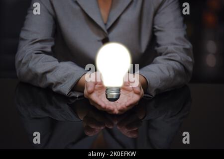 Geschäftsfrau hält Hand mit Glühbirne zur Hand, Geschäftsidee Konzept Stockfoto