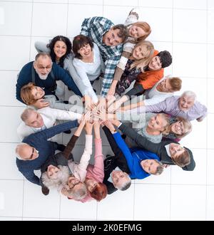 Gruppe älterer Menschen, die aus ihren Händen einen Turm bauen. Stockfoto