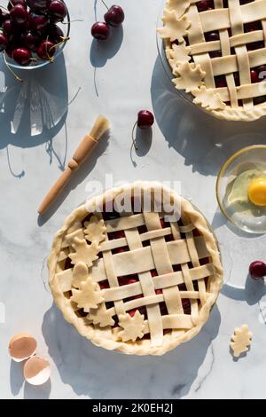Frisch gebackene, hausgemachte Kirschkuchen, die vor dem Backen zum Eierwaschen bereit sind. Stockfoto