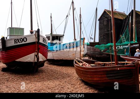 Eine Vielzahl von alten Fischerbooten im Besitz der Fischer, Museum auf dem Kiesstrand der Stade vor zwei hohen Netzläden, Hastings ausgestellt Stockfoto